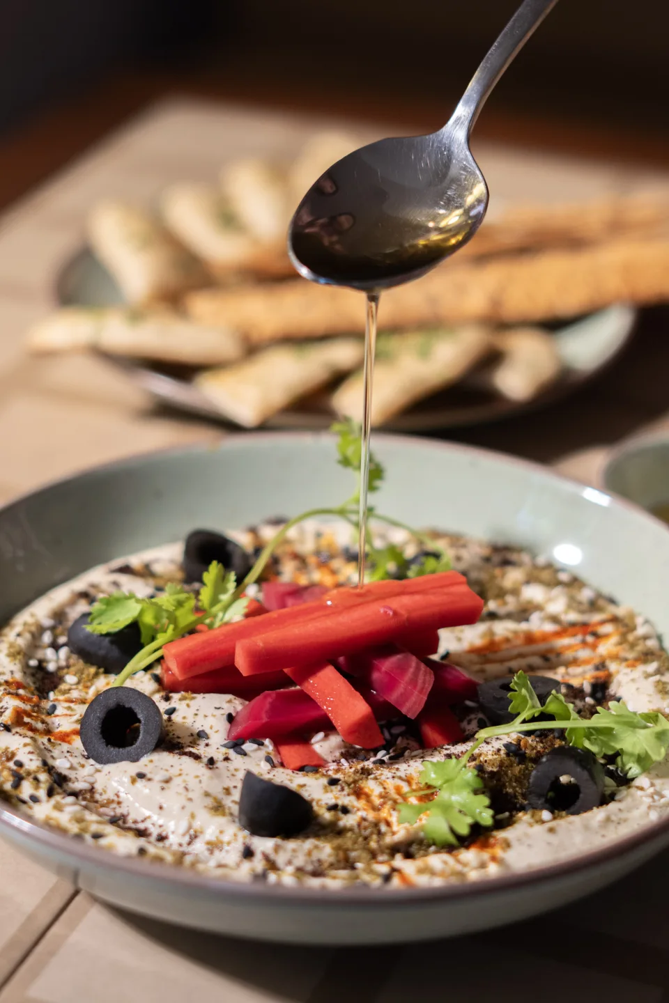 A spoon pouring dressing over a colourful salad