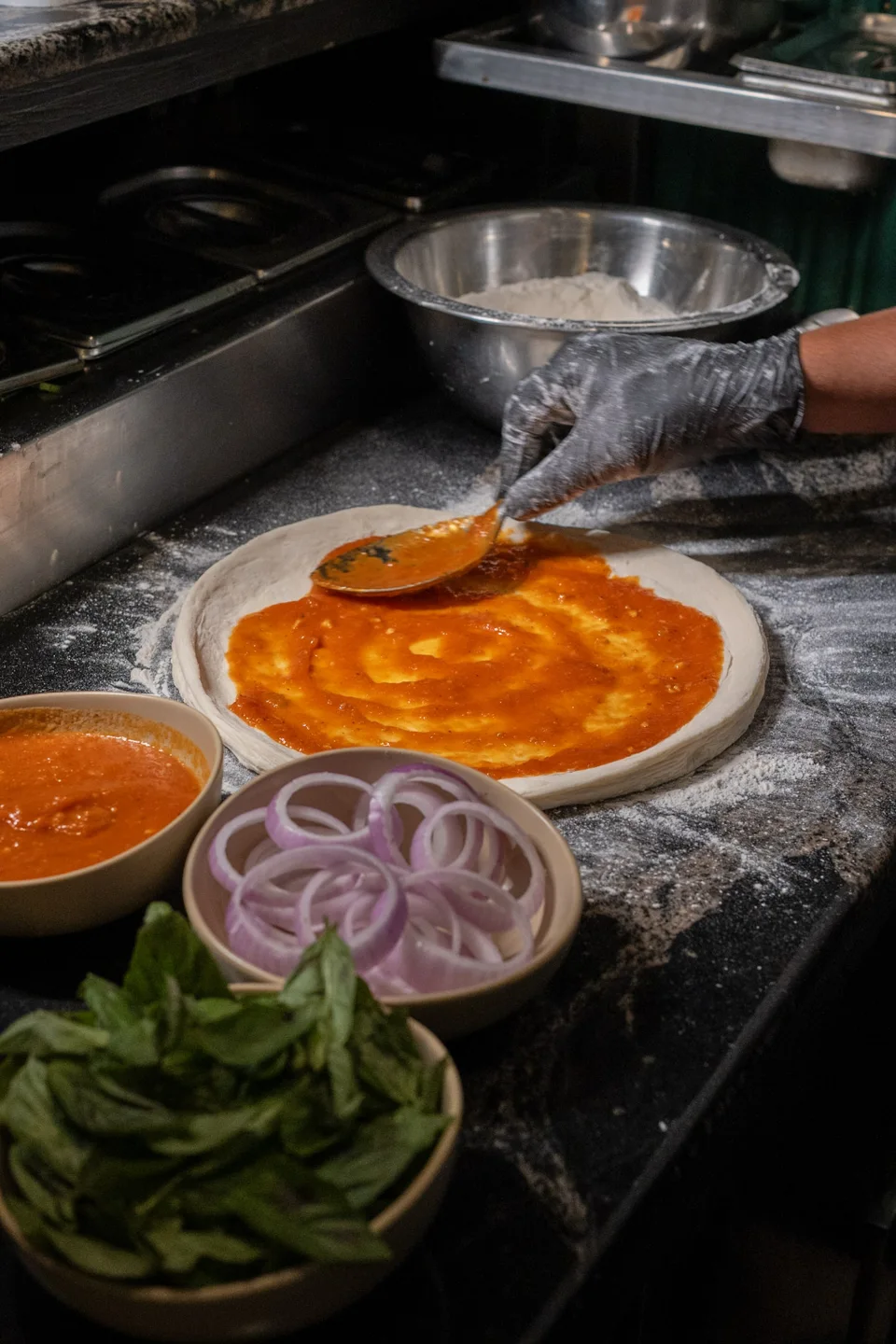 Tomato sauce being spread onto fresh pizza dough