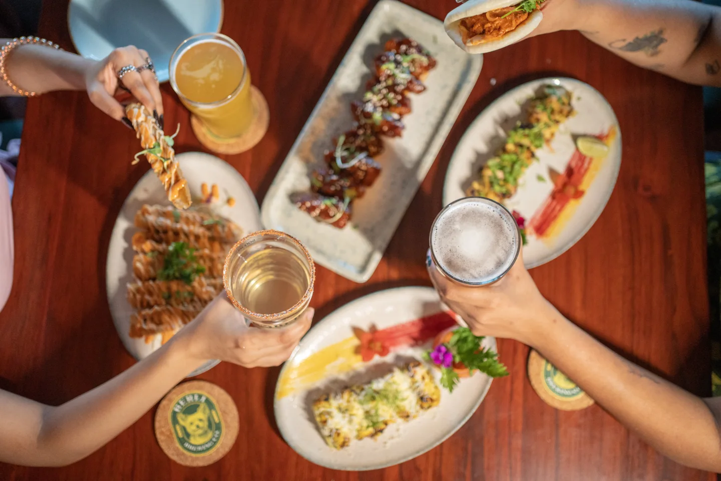 Friends raising drinks over a table of colourful shared dishes